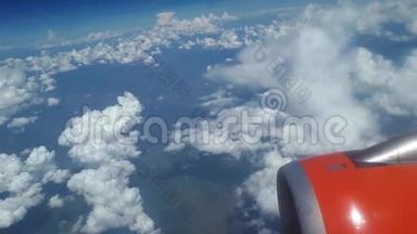 从飞机窗口到蓝天和白云的视野，飞机机翼上的一个橙色涡轮机，可以看到