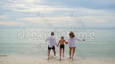 幸福的一家人牵着手沿着海岸<strong>奔跑</strong>。 在水里<strong>奔跑</strong>会产生飞溅