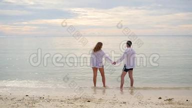 幸福的一家人牵着手沿着海岸奔跑。 在水里奔跑会产生飞溅