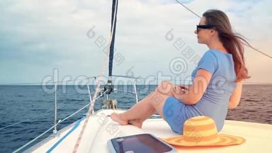 穿着黄色帽子和蓝色裙子的女人在海洋的夏季在游艇上休息。 慢动作