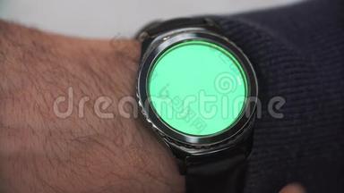 男子手势在圆形屏幕上现代智能手表与绿色屏幕色度键内容。 手表在他右边