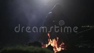 晚上坐在篝火旁的男人剪影。