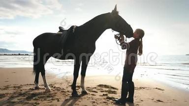 美丽的女孩在海滩上照顾她的马。 把注意力集中在女孩身上。