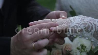 新娘在新郎`手指上戴戒指。 新郎把新娘的结婚戒指戴在手指上。 结婚双手戴戒指