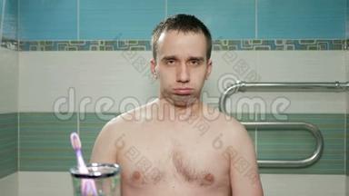 年轻有魅力的男人在酒店房间的浴室里展示着小小的肌肉。 他一只手和一只手都很烦人