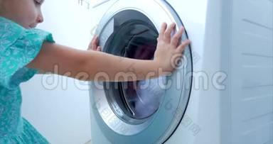 可爱的孩子看着洗衣机里面。 气缸旋压机.. 工业概念洗衣机