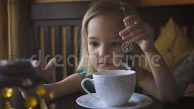 一个小孩在一家舒适的咖啡馆里吃早餐。 一个可爱的<strong>女孩喝茶</strong>享受早餐。