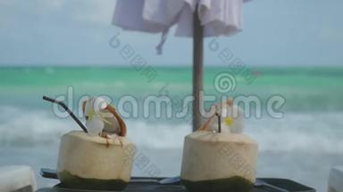 热带新鲜椰子鸡尾酒在海滩咖啡馆与绿松石海背景和变化的重点，以海。3840x2160