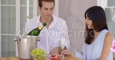微笑的年轻夫妇倒着香槟喝酒