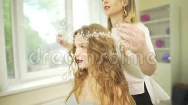 专业美发师发型师在金发波浪型女模特头上戴珠宝首饰，戴着珍珠皇冠