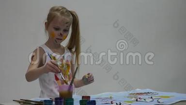 小女生。 <strong>可爱</strong>的小女孩画家在桌子上<strong>画画</strong>，在她的衣服上<strong>画画</strong>。 慢动作