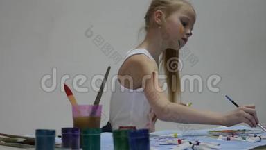 <strong>小女生</strong>。 可爱的<strong>小</strong>女孩画家在桌子上画画，在她的衣服上画画。 慢动作