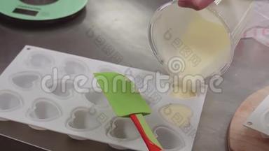 将奶饼从量杯中倒入塑料心形成型皿