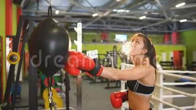 年轻女子拳击手在与拳击俱乐部的教练进行<strong>赛前</strong>热身时打拳击袋