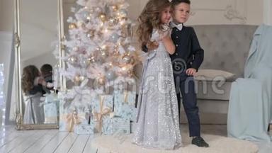 男孩和女孩在圣诞树背景上特写。 穿着漂亮衣服的孩子