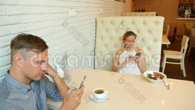 一对在咖啡馆。 男人和美女约会。 每个人都在看他的手机。 4k. 慢动作