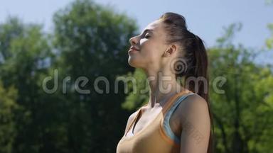 阳光明媚的一天，年轻的黑发女人在公园跑步后喘<strong>口气</strong>。