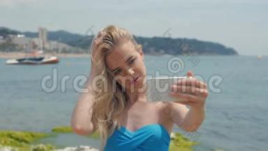 暑假海滩度假女孩用智能<strong>手机拍摄</strong>有趣的<strong>手机</strong>自拍照片。 可爱的戴蓝色太阳镜的亚洲女人