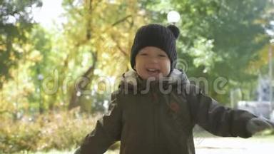 快乐的小男孩在秋天公园跑步。 小孩子在秋步上玩耍。 金叶的秋林