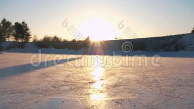 特写，低角度视角：快乐的女人在当地公园冰冻的池塘上快速滑冰，在金色的日落下，在神奇的圣诞节