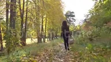 美丽的黑发女孩走在秋天的森林里，拿着一个野餐篮。 4Ksteatam视频