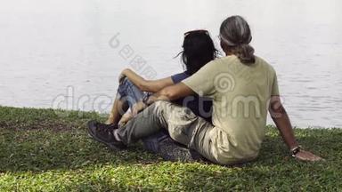 一对相爱的夫妇坐在湖边看水