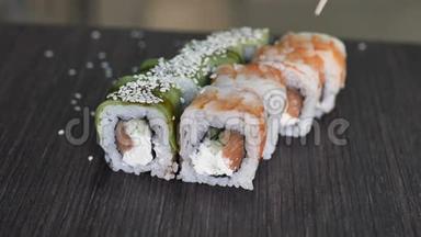 筷子的特写镜头将<strong>寿司</strong>卷在盘子或<strong>拼盘</strong>上。在日本酒吧餐厅提供。顶部