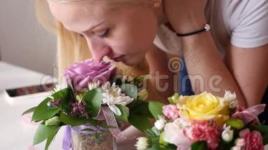 年轻漂亮的女孩正在小花瓶里闻着美丽而明亮的小花，抚摸着树叶，4K