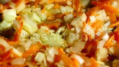 在煎锅里，用洋葱和胡萝卜炒。 在煎锅中加入青和冷冻红辣椒。