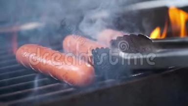 美味多汁的香肠烤火。 厨师在烤架上准备香肠。 扔在烤架上翻过来