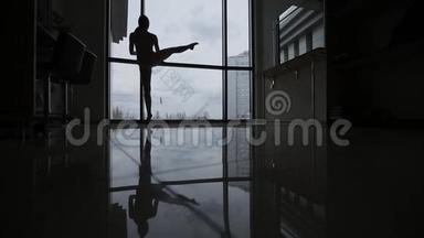 工作室里一个年轻的芭蕾舞演员热身。 画室里镜子地板上芭蕾舞演员的倒影，剪影。