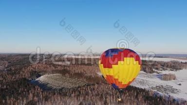 空中拍摄的人们乘坐一个大明亮的气球飞越冬季森林。
