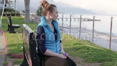 美丽的年轻女子坐在沙滩上的木凳上，看着镜头。 特写镜头。 高清<strong>1920</strong>x1080..