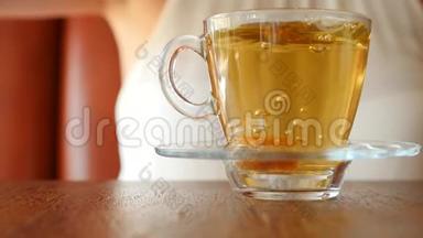 女孩把一块红糖放在一个透明的杯子里，上面有绿茶。 气泡上升。 慢动作。