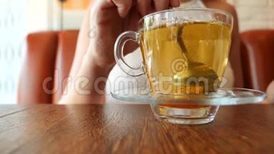 女孩把一块<strong>红糖</strong>放在一个透明的杯子里，上面有绿<strong>茶</strong>。 气泡上升。 慢动作。