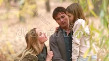 一家人站在公园里谈笑风生，父亲抱着女儿
