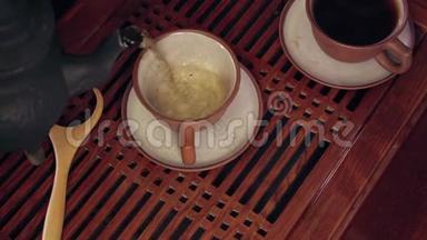 中国传统茶道的动作.. 在一个杯子里用粘土茶壶倒茶。 两个茶壶放在软的焦点上