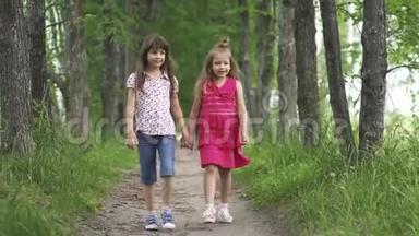 两个小女孩<strong>牵着</strong>手走在绿色的小巷里。 孩子们在户外散步。 两个小妹妹。 慢动作