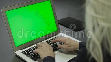 笔记本电脑键盘上的特写镜头打字。 带有绿色屏幕的笔记本电脑