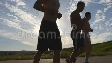 日落时分，强壮的男人在乡间小路上慢跑的剪影。 马拉松跑男子慢跑训练组