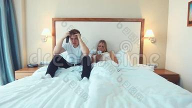 幸福的夫妻<strong>躺</strong>在<strong>床上看</strong>电视，用智能<strong>手机</strong>