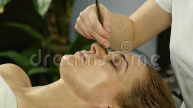 美丽的女人在水疗中心做面部按摩。 美容院面部皮肤护理。 慢动作