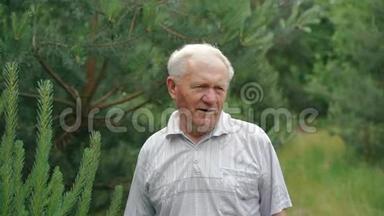 一个<strong>满脸皱纹</strong>的老人呼吸着常绿的树叶，对着镜头微笑