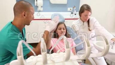 坐在牙科椅上给牙医和助理击掌的女孩