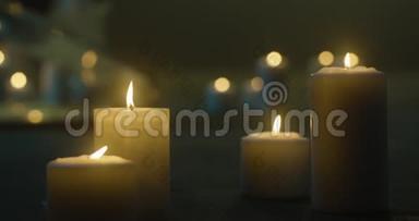 地板上有很多燃烧的蜡烛。 蜡烛在黑暗中燃烧，玻璃烛台，蜡烛的黄色火焰，烛台