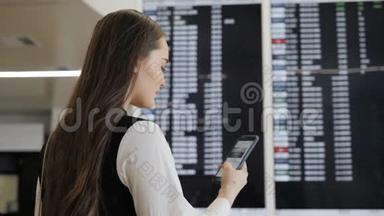 旅行妇女在机场使用智能手机。 年轻的白种人旅行者用手机应用程序检查登机时间。