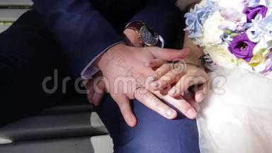 新婚夫妇`手里拿着结婚戒指。 新娘和新郎在鲜花或婚礼花束上戴着结婚戒指。 新婚夫妇