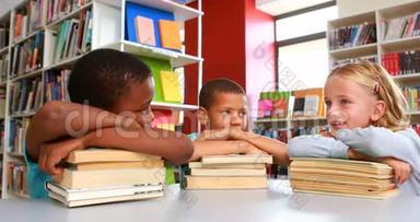 学校里的孩子们靠在图书馆的一叠书上