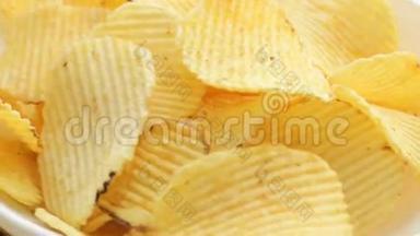 旋转不健康的有害食物，黄色美味的土豆肋脆薯片随机躺在白色的桌子背景上，特写。