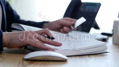 在家里或办公室的办公桌上，把一只手写在议程上的女人紧紧地